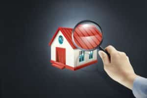 person holding magnifier glass over house