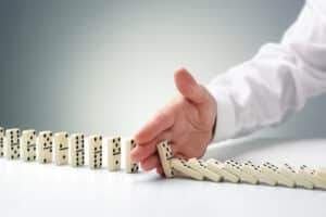 man stopping dominoes from falling over